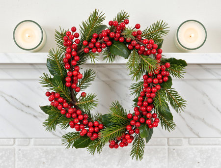 Christmas wreath with holly berries and burning candles on white marble backgroundの素材