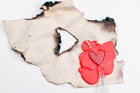 mark in the shape of a heart made of red wax on a piece of burnt paperの写真素材