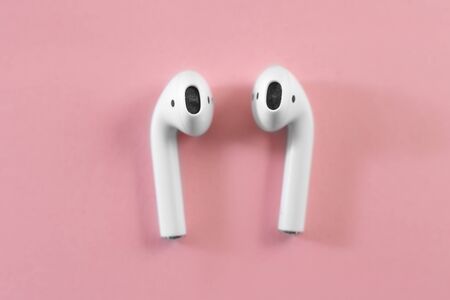 White headphones with box case on pink background. Modern technology pods with air connection....