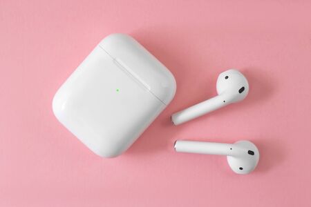 White headphones with box case on pink background. Modern technology pods with air connection....