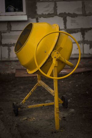 yellow concrete mixer on the construction of a house in the village