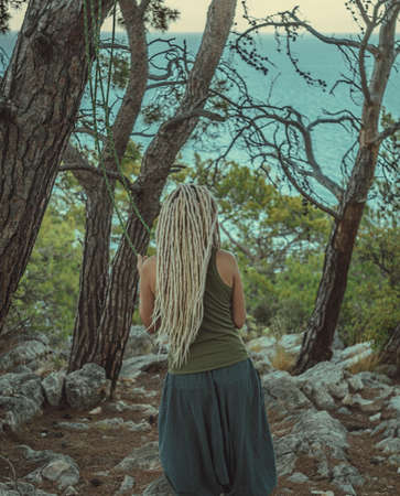 a rastafarian girl with dreadlocks walks on the rocks. 4k