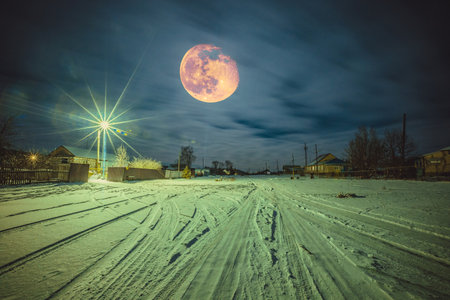Moon at night over the village in winter.の写真素材