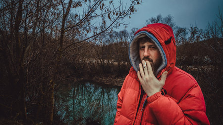 A guy with a beard stands by the river.