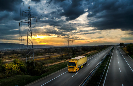 Highway transportation with yellow lorry at sunsetの写真素材