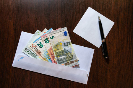 White envelope with Euro bills over wooden background