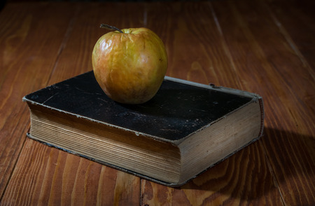Old book and an apple on a rustic wooden tableの写真素材