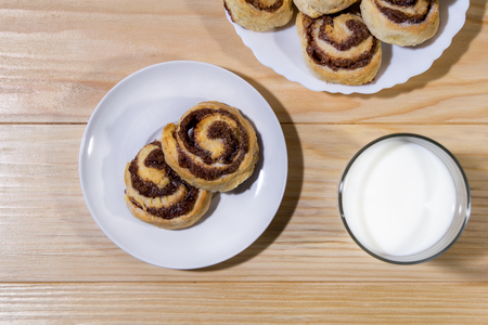 Sweet cinnamon rolls with milk on a wooden tableの写真素材