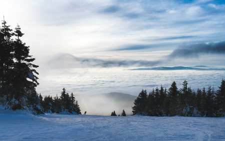 Single skier silhouette at a the piste with fog and clouds in the backgroundの写真素材