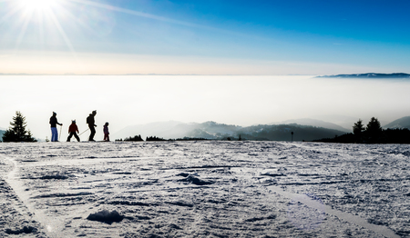 Family skiing silhouettes at a the piste with fog and clouds in the background, Sunny Valley piste, Kopaonik, Serbiaの写真素材