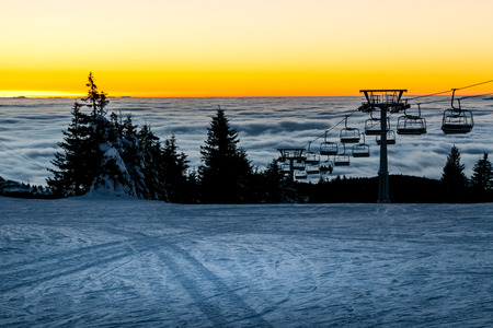 Chair ski lift with skiers silhouettes at sunsetの写真素材