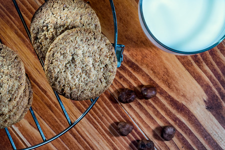 Hazelnut Cookies on a round cooling rack with Milk and Nuts at the old wooden tableの写真素材