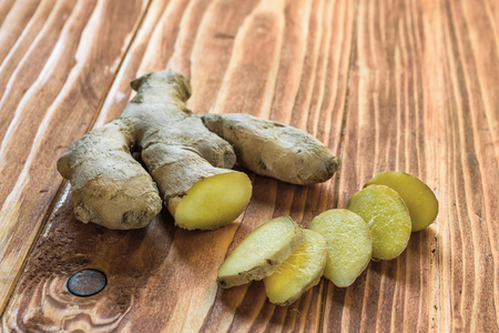 Fresh ginger root and ginger sliced on a wood table cutting boardの写真素材