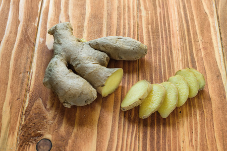 Fresh ginger root and ginger sliced on a wood table cutting boardの写真素材