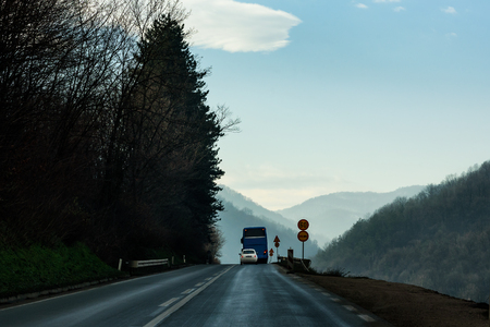 Mountain road leading to the vacation with the far hills in the mistの写真素材