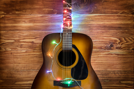 Guitar with Christmas lights on a wooden wall backgroundの写真素材