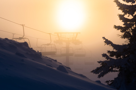 Chair ski lift with skiers sillhouettes at sunsetの写真素材