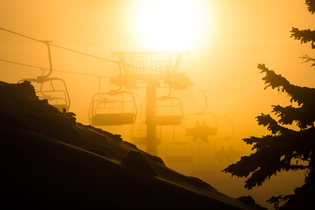 Chair ski lift with skiers sillhouettes at sunsetの写真素材