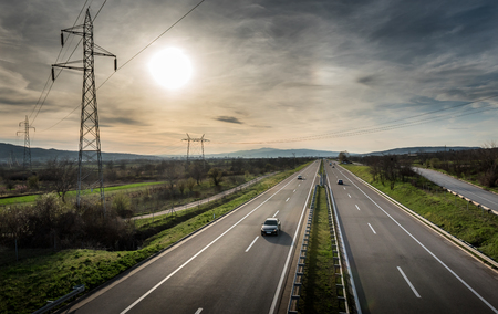 Highway Traffic on a straight road at sunset through pastoral landscapeの写真素材