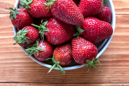 Fresh ripe strawberries in a bowl on a wooden tableの写真素材