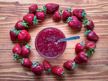 Homemade strawberry jam in a a glass bowl with fresh ripe strawberries on a wooden tableの写真素材