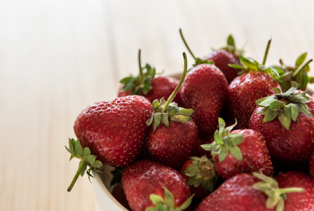 Fresh ripe strawberries in a bowl on a wooden tableの写真素材