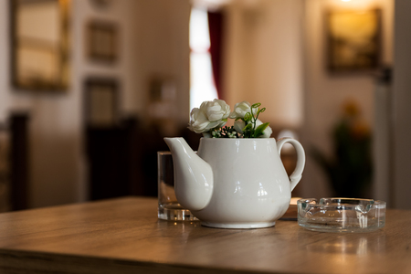 Indoor Restaurant Decoration with Ceramic Milk Pot with Flowers on a Wooden table with a gallery in the backgroundの写真素材