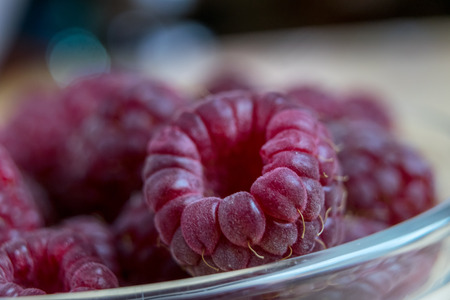 Fresh organic raspberries in a glass bowl on wooden tableの写真素材