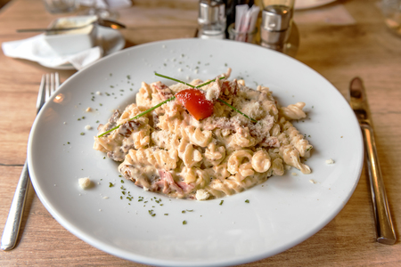 Colorful plate with penne pasta with prosciutto and spinach on a tableの写真素材