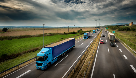 Caravan or convoy of Blue Lorry  trucks in line on a country highway