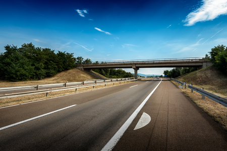 View of a multi lane highway with fog markings and  a crossing in distanceの写真素材