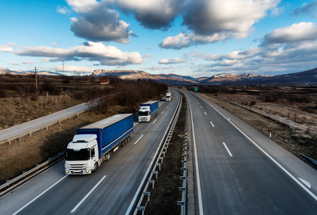 Caravan or convoy of lorry trucks on country highway under a dramatic skyの写真素材