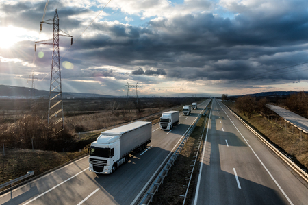 Caravan or convoy of lorry trucks on country highway under a dramatic skyの写真素材