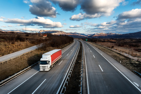 Single lorry truck on country highway under a beautiful skyの写真素材