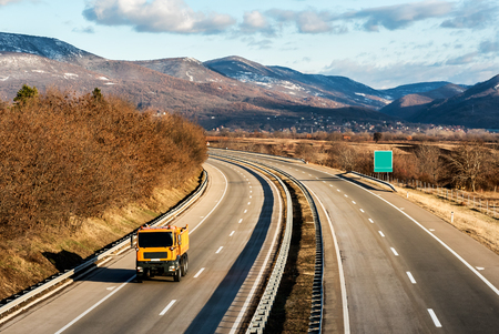 Yellow utility truck on country highway under a beautiful skyの写真素材