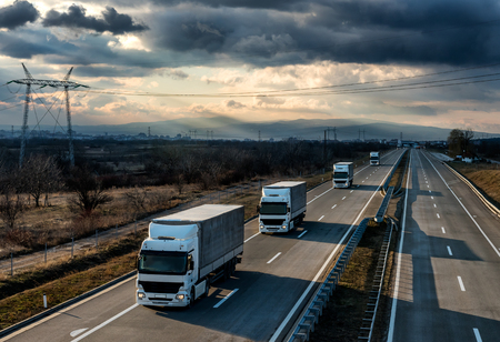 Caravan or convoy of lorry trucks on country highway under a beautiful skyの写真素材