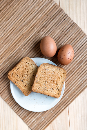 Two Slices of Toast Bread and and Two Boiled Eggs on a Wooden Table Setupの写真素材