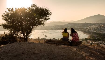 Bodrum, Turkey - August 21, 2019. Girl friends enjoying Beautiful and relaxing sunset view on a Gumbet Bay. Bodrum. Mugla Province, Turkey.のeditorial素材