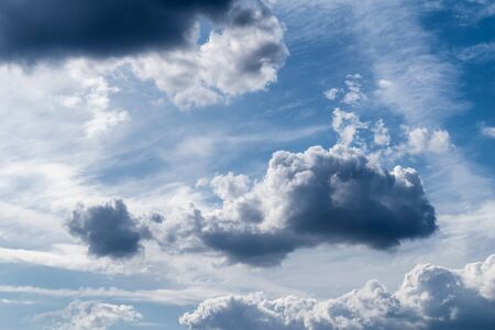 White cumulus clouds and a blue sky with sun rays after a storm