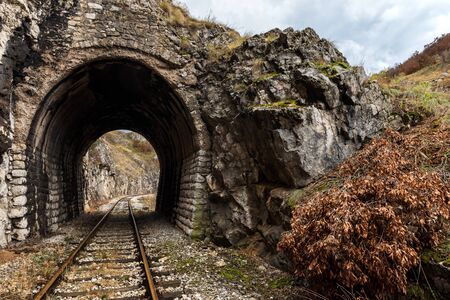 Old abandoned railway passing through short tunnels in picturesque rural sceneryの写真素材