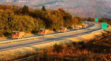 Convoy or caravan of red utility trucks on a highway. Highway transportation with red utility tracks...