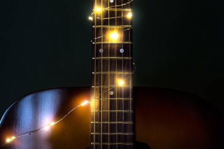 Guitar with Christmas lights with a soft focused decorated Christmas Tree in the backgroundの写真素材