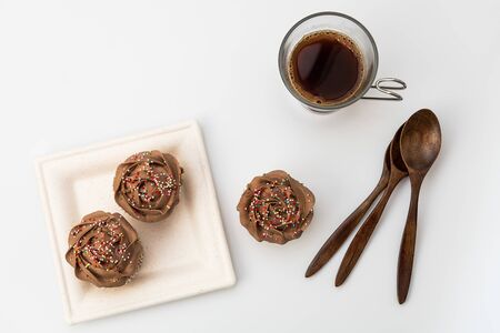 Top View of Chocolate muffins on a white background with a cup of coffee and wooden spoons. Homemade baking, close up.の写真素材