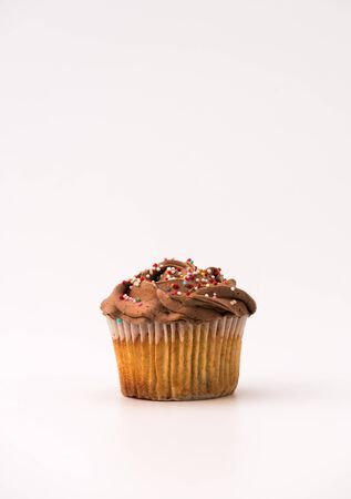 Delicious chocolate muffin, isolated on white background. Muffin and paper, sweet food or unhealthy eating theme.の写真素材