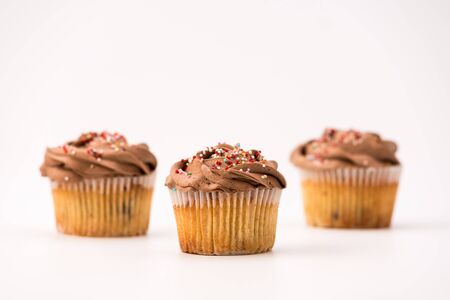 Delicious chocolate muffins, isolated on white background. Muffin and paper, sweet food or unhealthy eating theme.の写真素材