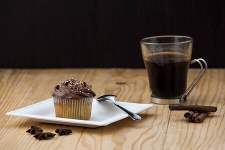Chocolate Muffin with hot Cup of coffee, cinnamon sticks and Anise stars on a wooden tableの写真素材