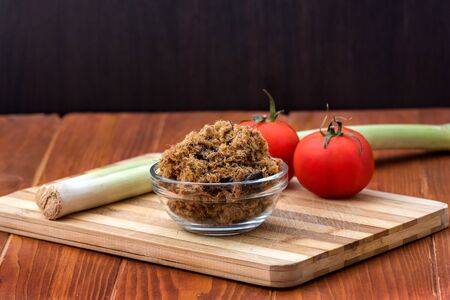 Domestic salty fried Pork greaves, duvan cvarci, in a Glass Bowl with Tomato and Leek on a Cutting Board and on Wooden Tableの写真素材