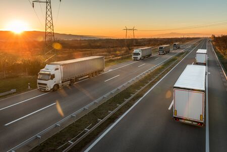 Convoys of transportation trucks passing each other  on a highway. Highway transportation with lorry tracksの写真素材