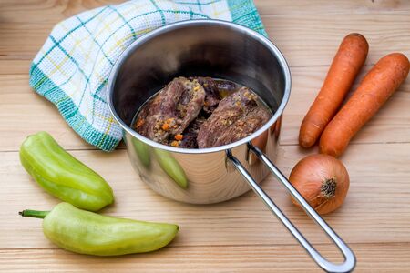 Traditionally made beef steaks in sauce with carrots and onions offered as closeup in a cast iron Sauce Pan on a wooden tableの写真素材