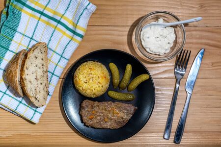 Prepared beef steak with rice risotto, pickles and sauce on black plate on wooden table backgroundの写真素材